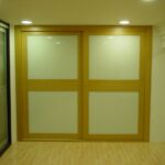 Frente corredero combinando cristal lacado blanco y perfiles en roble