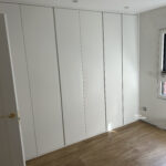 Frente de armario de hojas lisas abatibles lacado blanco con tirador uñero fresado vertical largo en toda la puerta